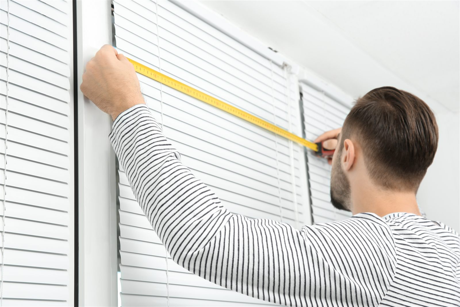 Instalador midiendo blinds para una ventana